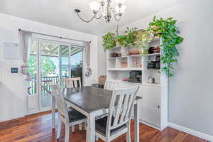 Dining area with dark wood-style floors and a chandelier