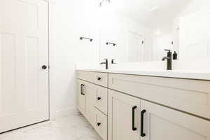 Full bath with double vanity and light marble finish flooring