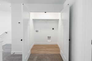 Laundry area featuring hookup for a washing machine, hookup for an electric dryer, light colored carpet, and light wood-style flooring