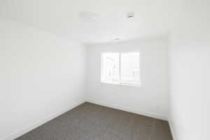 Carpeted spare room featuring baseboards