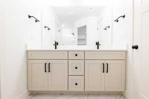 Bathroom featuring double vanity and light marble finish flooring