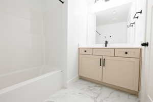 Bathroom featuring light marble finish floors, vanity, and shower / bathtub combination