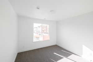 Carpeted spare room featuring baseboards and a smoke detector