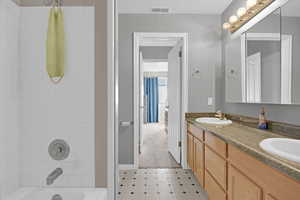 Bathroom featuring double vanity and tub / shower combination