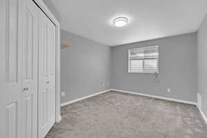 Unfurnished bedroom with light colored carpet, a closet, and a textured ceiling