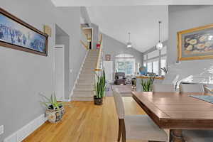Dining space featuring wood finished floors, high vaulted ceiling, stairway, and ceiling fan