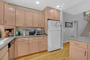 Kitchen featuring light brown cabinets, freestanding refrigerator, light wood-style floors, light countertops, and recessed lighting