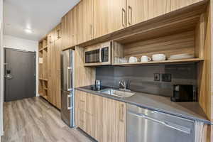Kitchen featuring open shelves, stainless steel appliances, modern cabinets, light wood-type flooring, and light brown cabinetry