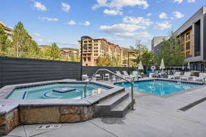 Community pool with a patio and a hot tub