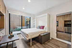 Bedroom featuring dark wood-type flooring, access to exterior, and recessed lighting