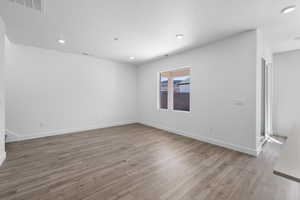Empty room featuring light wood-type flooring, recessed lighting, and a textured ceiling