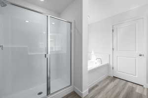 Full bath featuring a stall shower, a garden tub, and light wood-type flooring