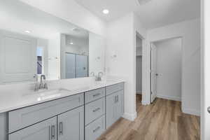 Full bathroom featuring a stall shower, double vanity, a walk in closet, light wood finished floors, and recessed lighting
