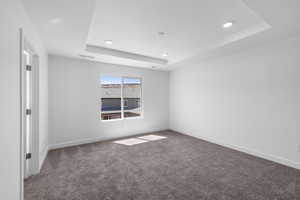 Spare room with a raised ceiling, carpet, and recessed lighting