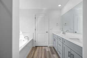 Bathroom featuring double vanity, a garden tub, and light wood-type flooring
