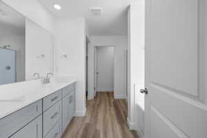 Full bath featuring double vanity, light wood-type flooring, a stall shower, and recessed lighting