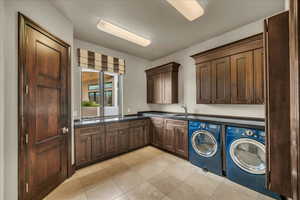 Laundry room with cabinet space, washing machine and clothes dryer, and light tile patterned flooring