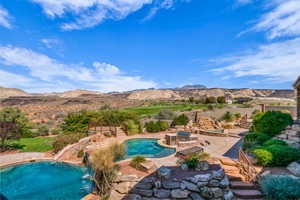 View of pool with a patio area, a mountain view, a water slide, and a hot tub