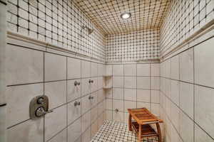 Full bathroom featuring a tile shower, tile walls, and recessed lighting