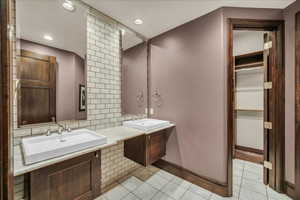 Bathroom with decorative backsplash, double vanity, a walk in closet, light tile patterned floors, and recessed lighting
