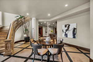 Dining space with inlaid floor details, recessed lighting, and stairway