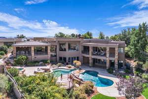 Rear view of property featuring an outdoor pool, stucco siding, a patio, and a jacuzzi