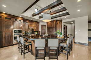 Kitchen featuring a breakfast bar area, glass insert cabinets, decorative light fixtures, dark stone counters, and oven