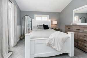 Bedroom with light carpet and lofted ceiling