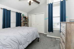 Bedroom with vaulted ceiling, dark carpet, ceiling fan, and a closet