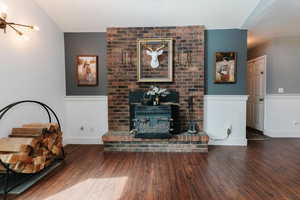 Living area featuring a wood stove, wood finished floors, and wainscoting