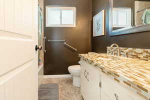 Bathroom featuring shower / tub combo, vanity, healthy amount of natural light, and decorative backsplash