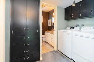 Laundry area featuring cabinet space, light carpet, and independent washer and dryer