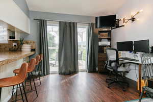 Home office with healthy amount of natural light and dark wood-style flooring