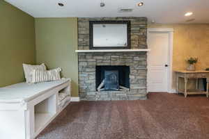 Living area featuring carpet floors, recessed lighting, and a stone fireplace