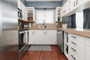 Kitchen featuring open shelves, white cabinetry, and appliances with stainless steel finishes