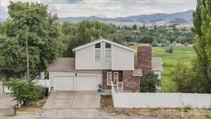 View of front of house with a mountain view, driveway, brick siding, and a chimney