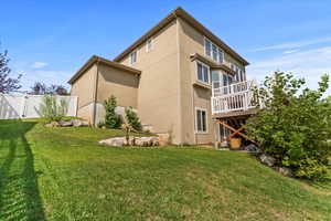Back of house featuring a yard, a deck, and stucco siding