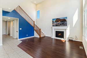 Unfurnished living room with a high ceiling, a tile fireplace, light tile patterned floors, stairway, and recessed lighting