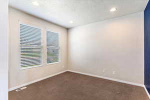 Carpeted spare room with a textured ceiling and recessed lighting
