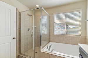 Full bathroom featuring vanity, a garden tub, a shower stall, and a textured ceiling