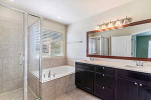 Bathroom featuring a garden tub, a stall shower, plenty of natural light, double vanity, and a textured ceiling