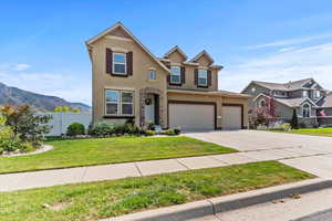 Traditional home with stucco siding, concrete driveway, a mountain view, and an attached garage