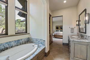 Ensuite bathroom featuring vanity, a garden tub, dark tile patterned floors, and recessed lighting