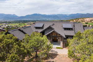 View of front facade with stone siding, a mountain view, and roof with shingles