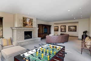 Game room featuring light colored carpet, a brick fireplace, and recessed lighting