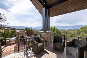 Wooden terrace with exterior kitchen, a mountain view, and a patio area