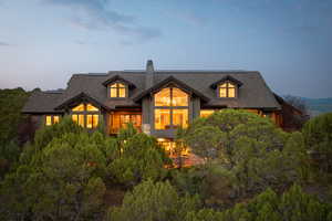 Back of property at dusk with a chimney and a shingled roof