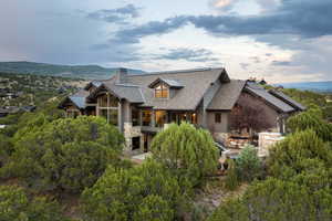 View of front facade featuring stone siding, a mountain view, a chimney, roof with shingles, and a balcony