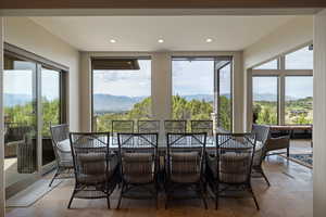 Sunroom / solarium with a mountain view, plenty of natural light, recessed lighting, and stone tile floors