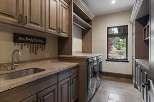Washroom featuring cabinet space, washing machine and clothes dryer, and stone tile floors